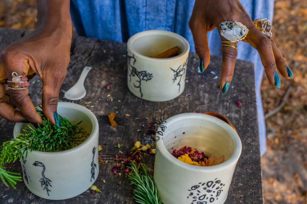 Woman's hands preparing herbal tea with artistic cups