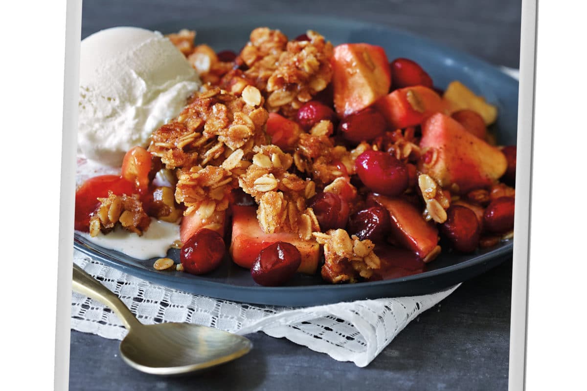 A close-up view of Apple Cranberry Crumble with vanilla ice cream on a blue plate.