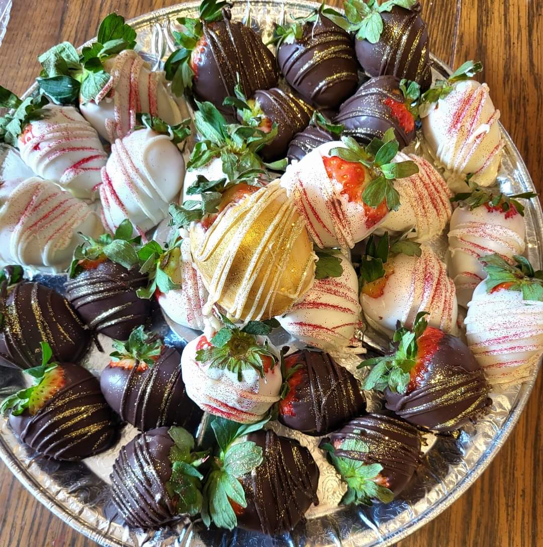 Platter of strawberries covered in white and dark chocolate with artistic drizzles.