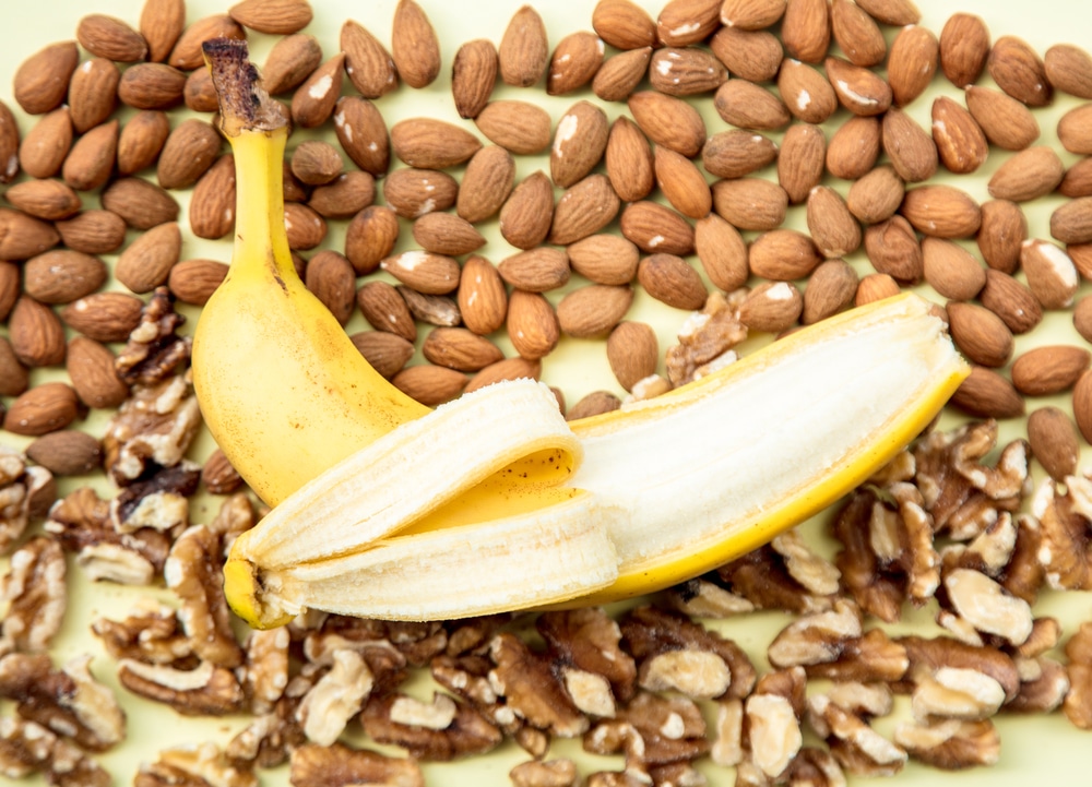 Half-peeled banana surrounded by almonds and walnuts
