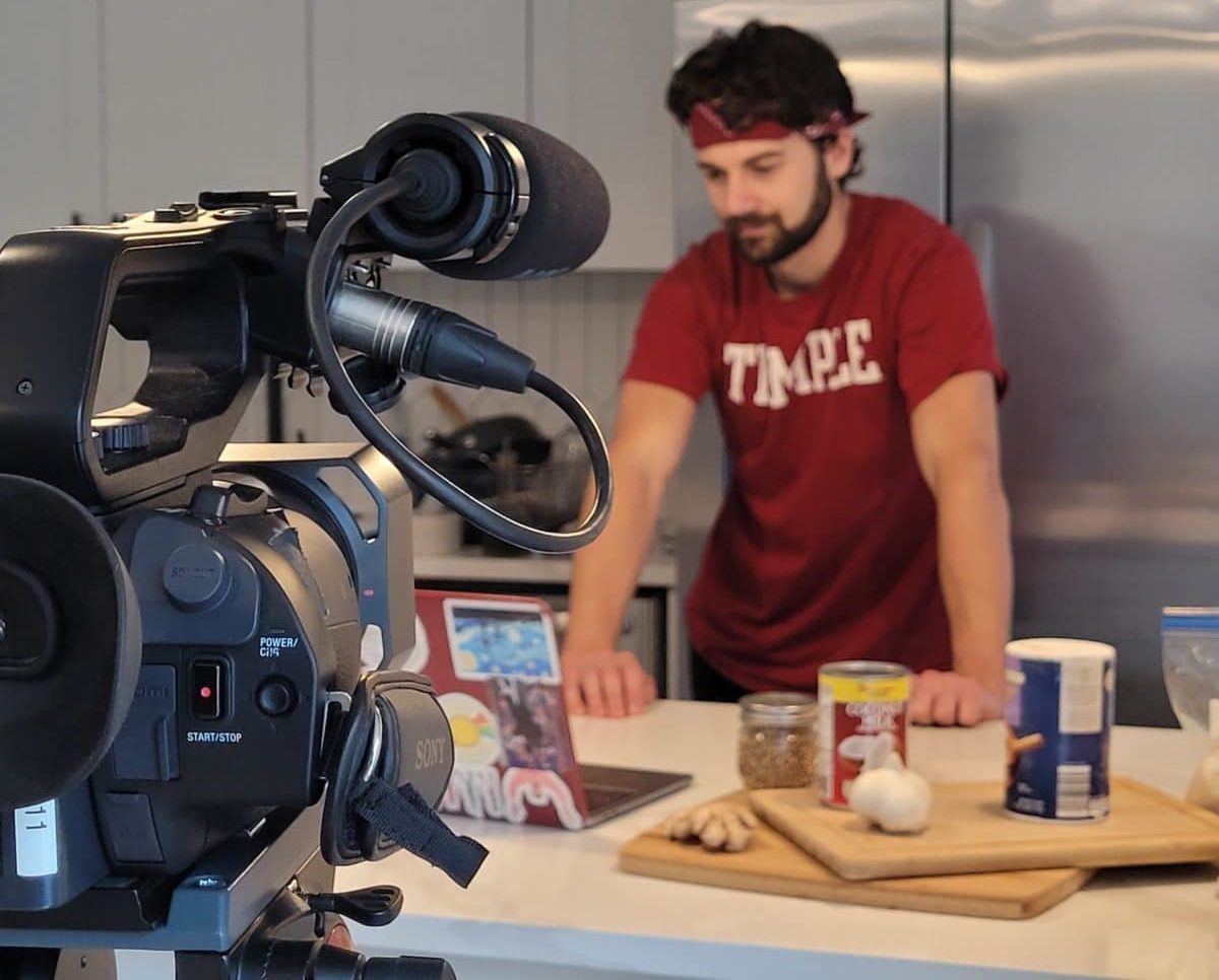 Man with red bandana working in kitchen with camera setup
