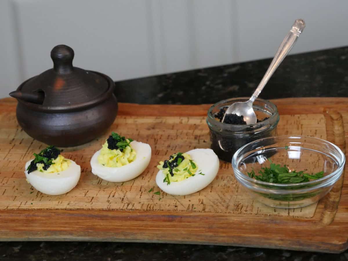 Deviled eggs stuffed with caviar and garnished with herbs