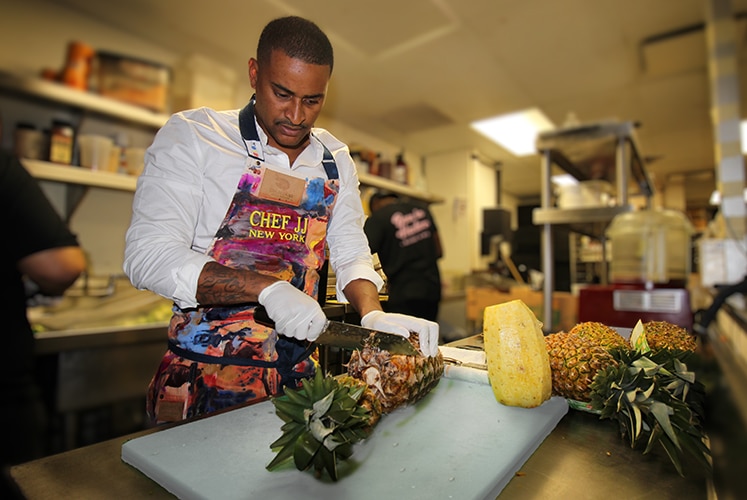 Chef JJ working diligently in the kitchen, prepping various fruits.