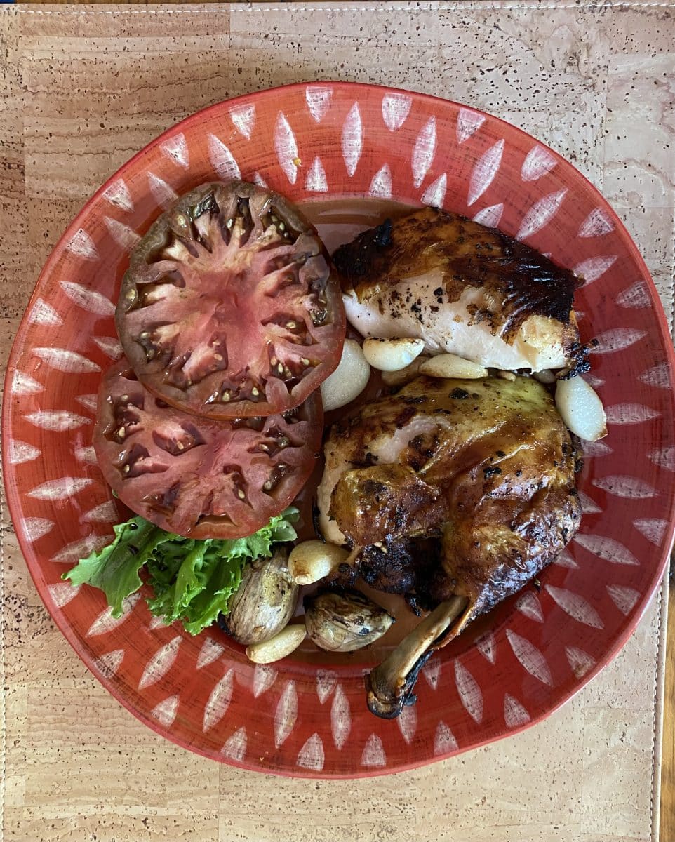 Grilled chicken with garlic cloves and sliced tomatoes