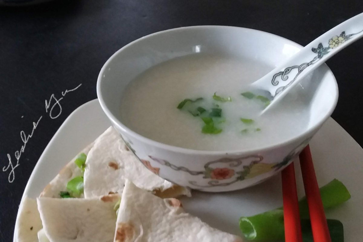 Bowl of congee with a side of scallion pancakes and green onions