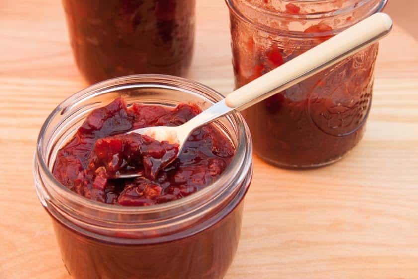 Glass jar filled with cranberry rose hip crab apple chutney.