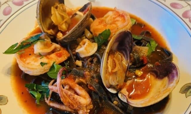 A bowl filled with cioppino, showcasing mussels, shrimps, and calamari in a rich tomato broth.