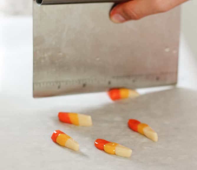 Pieces of multicolored candy corn on a cutting board.