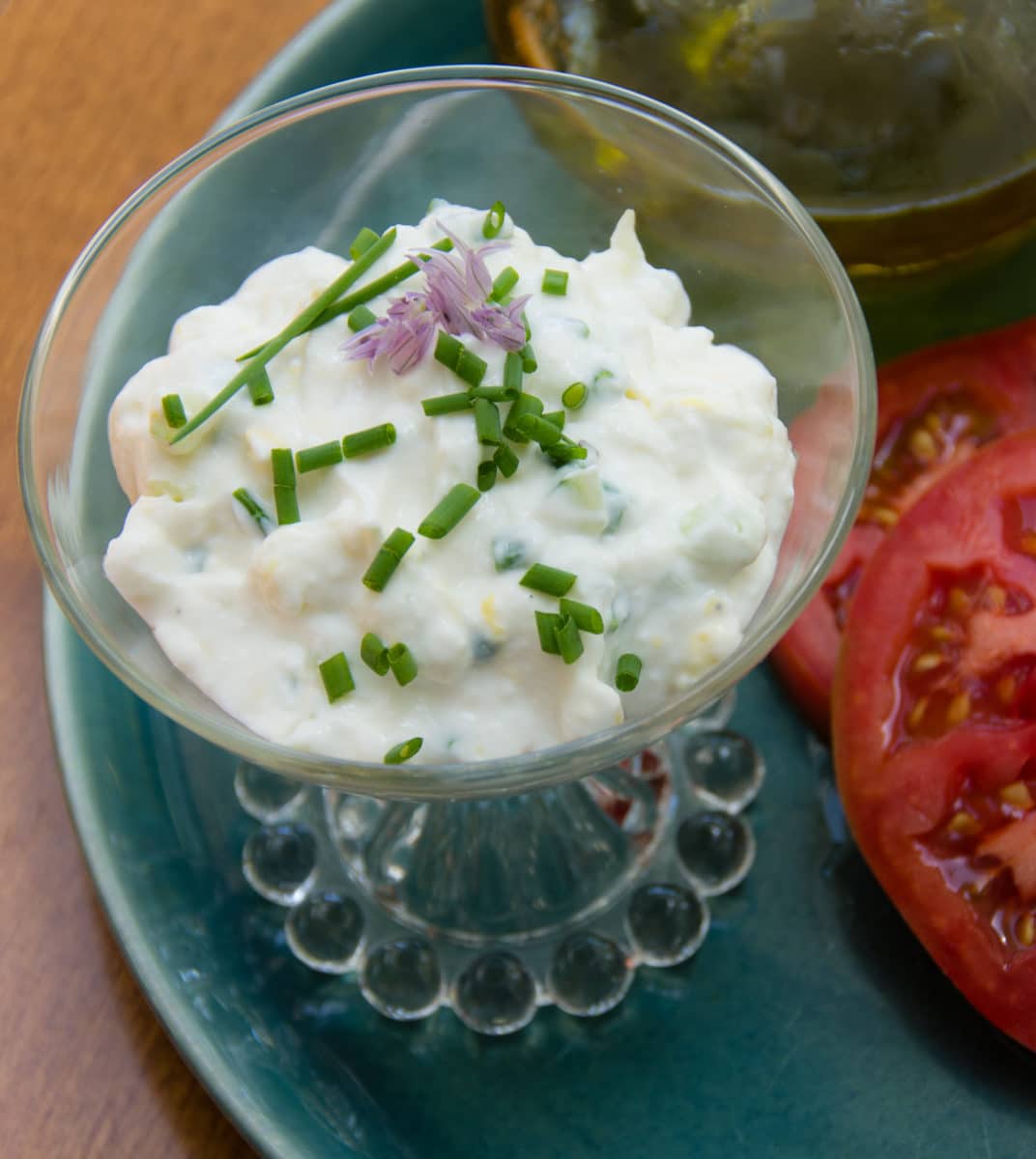 Ricotta spread garnished with chives in a glass dish