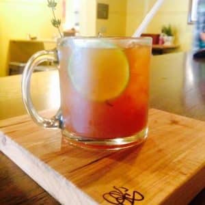 A colorful mocktail served in a glass mug on a wooden table.