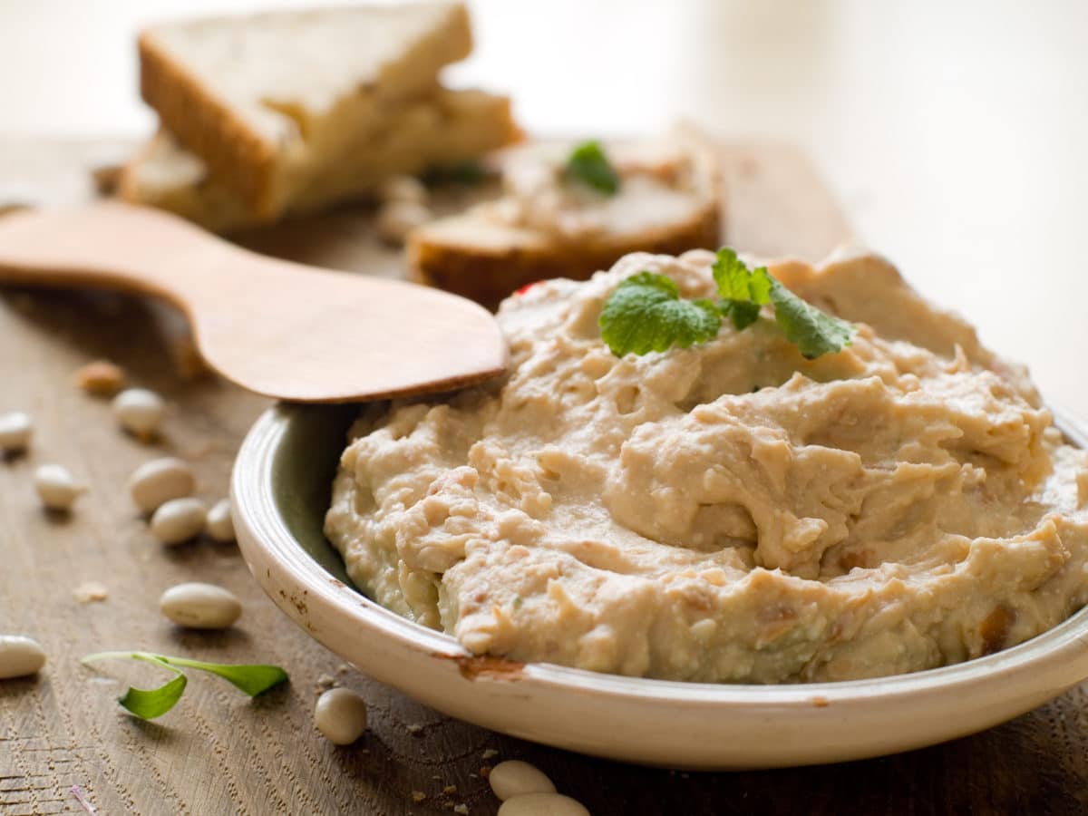 A creamy bowl of hummus dip accompanied by slices of fresh bread, ready for consumption.