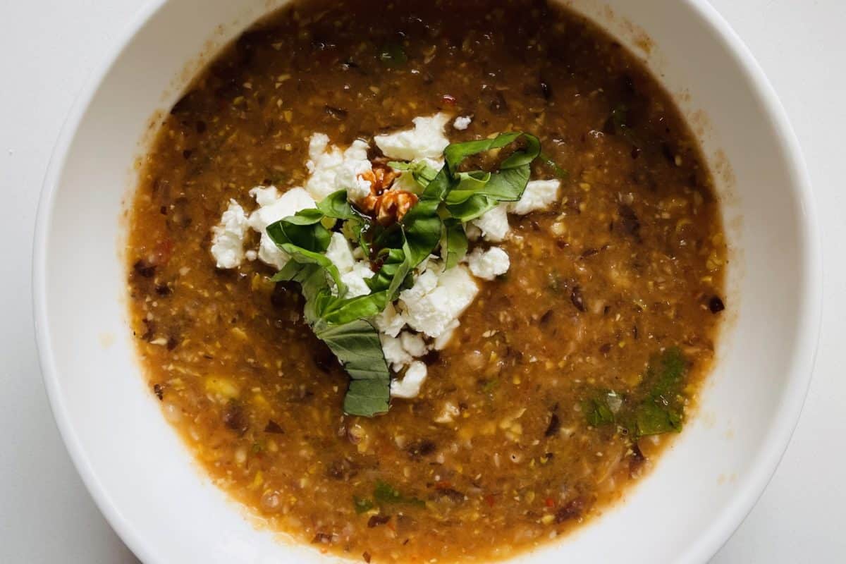 Thick and hearty black bean soup garnished with feta cheese and fresh basil leaves.