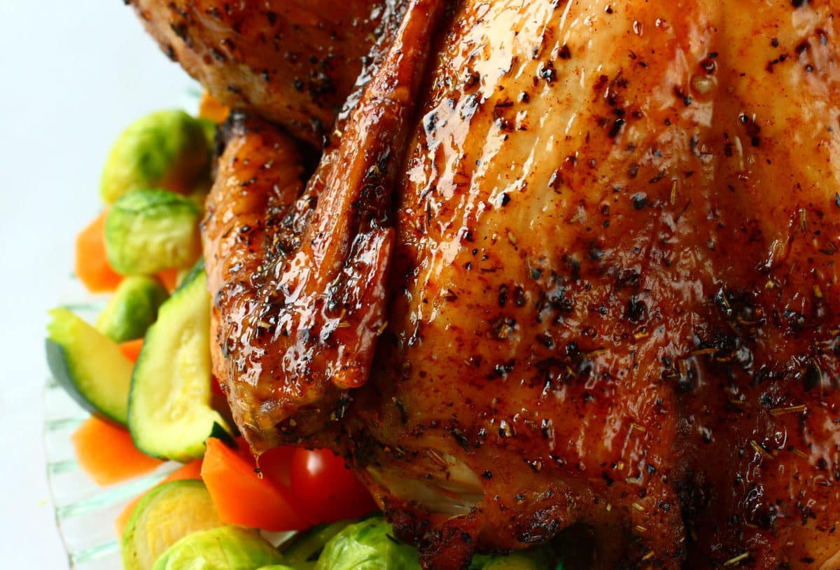 Close-up view of a perfectly roasted chicken with accompanying vegetables