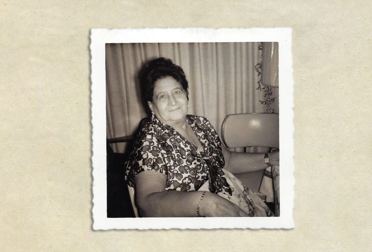 Black and white photo of a smiling woman in a patterned dress.