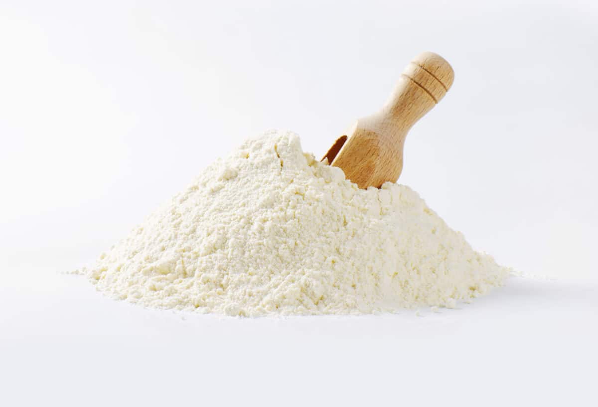 Pile of finely ground white flour with a wooden scoop embedded into it.