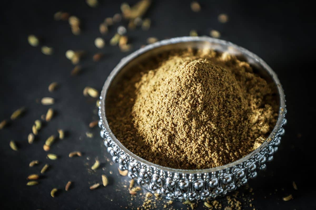 Close-up of garam masala powder in a decorative bowl.