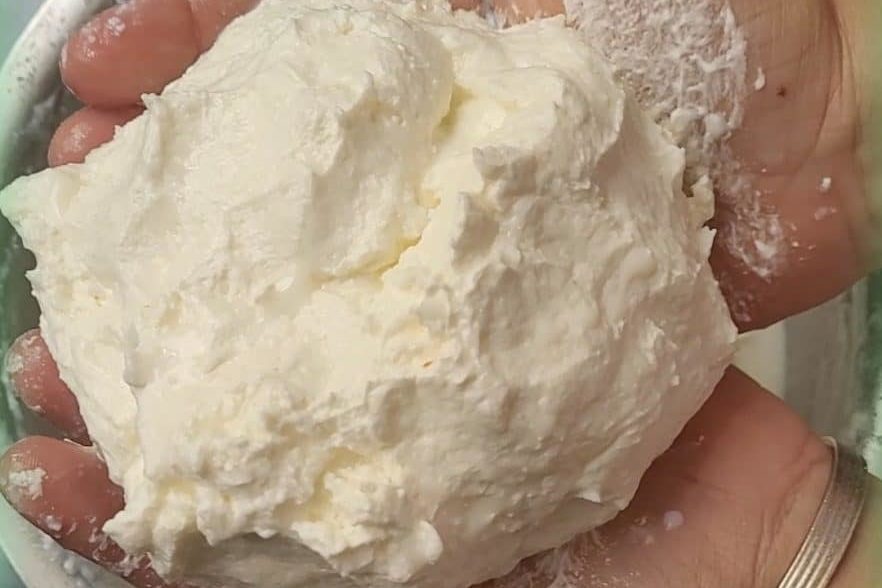 Hand holding a chunk of homemade white butter.