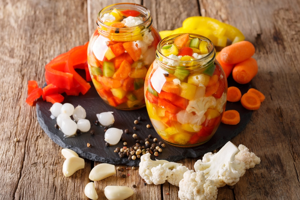 Close-up of Italian Giardiniera pickled vegetables in sealed glass jars.