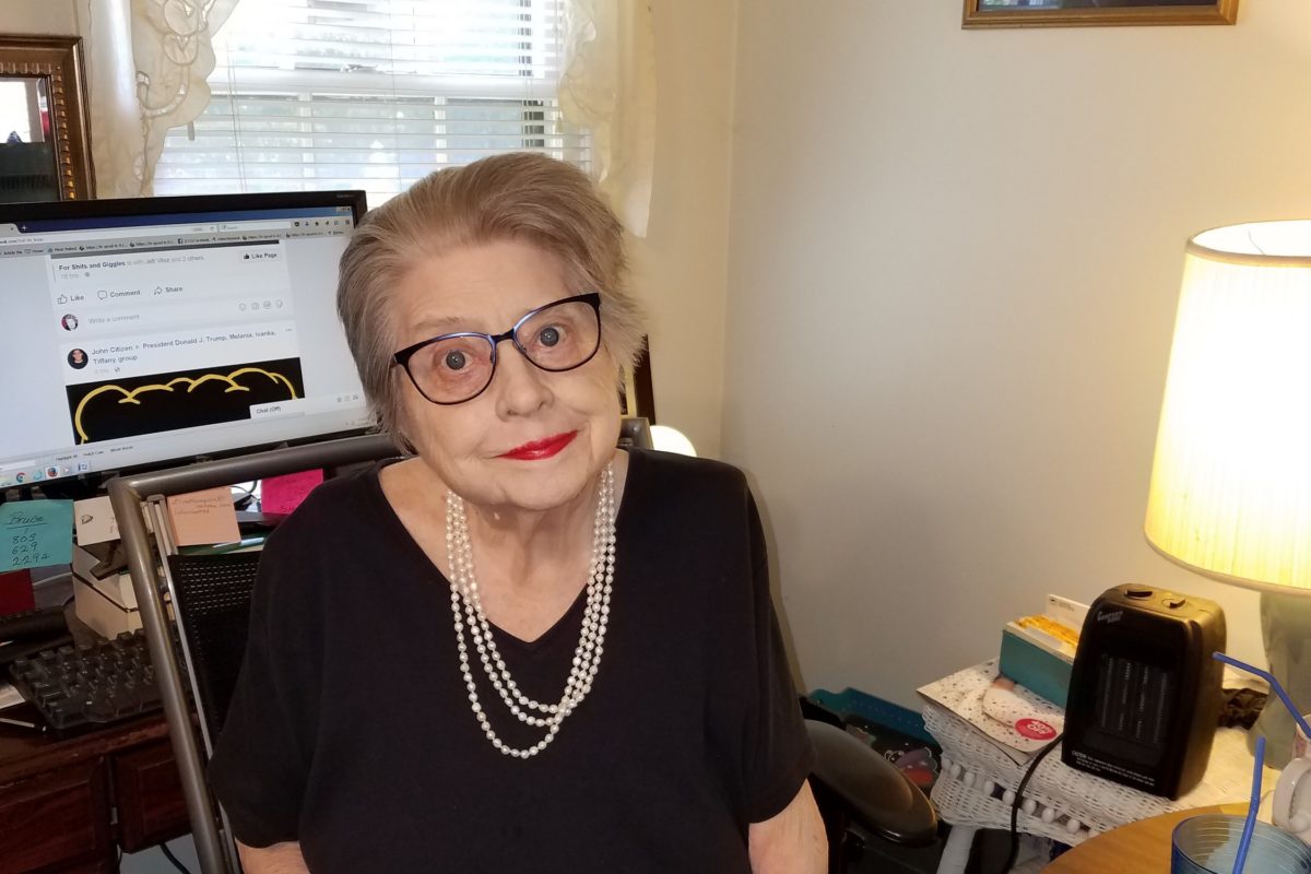 Lady with glasses sitting behind a computer desk.