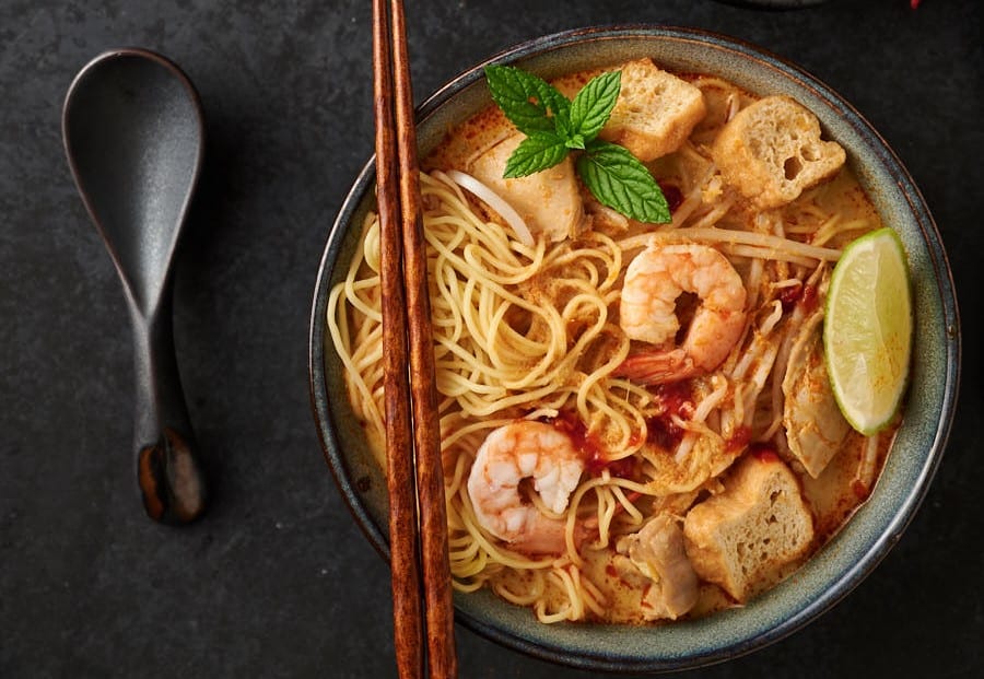 A top view of Malaysian curry laksa with shrimps, tofu, and noodles.
