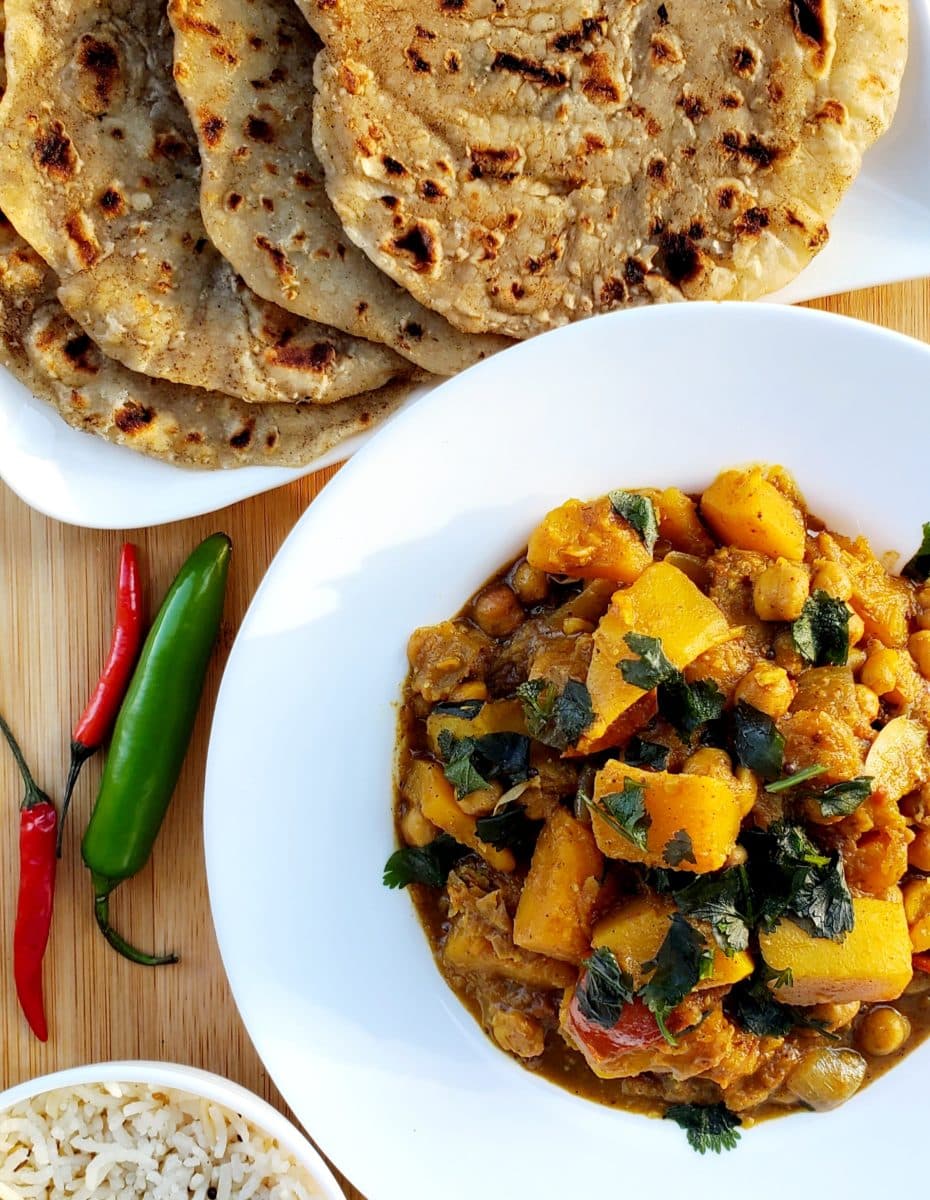 Grilled flatbread served alongside a vibrant dish of butternut squash and chickpeas cooked in coconut tomato masala.
