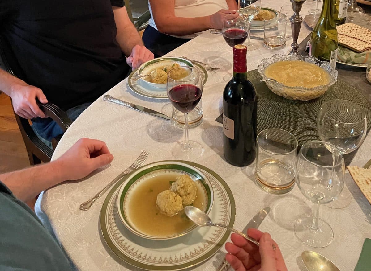 A dinner setting with matzo ball soup and wine on table