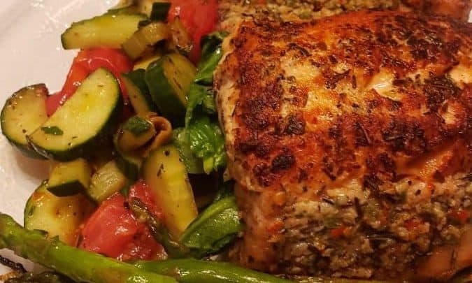 Grilled salmon stuffed with Mediterranean ingredients, served with sautéed vegetables.