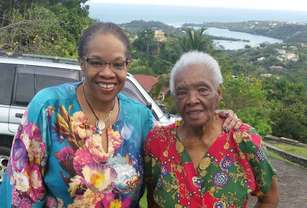 A smiling mother and daughter posing with a scenic backdrop.