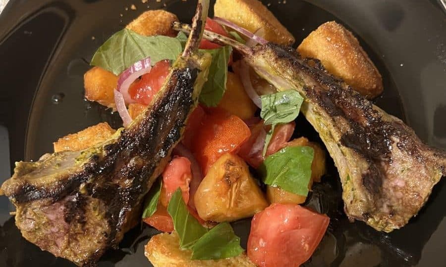 Pan-grilled lamb chops served with cornbread panzanella, tomatoes, greens, and peach brown butter.