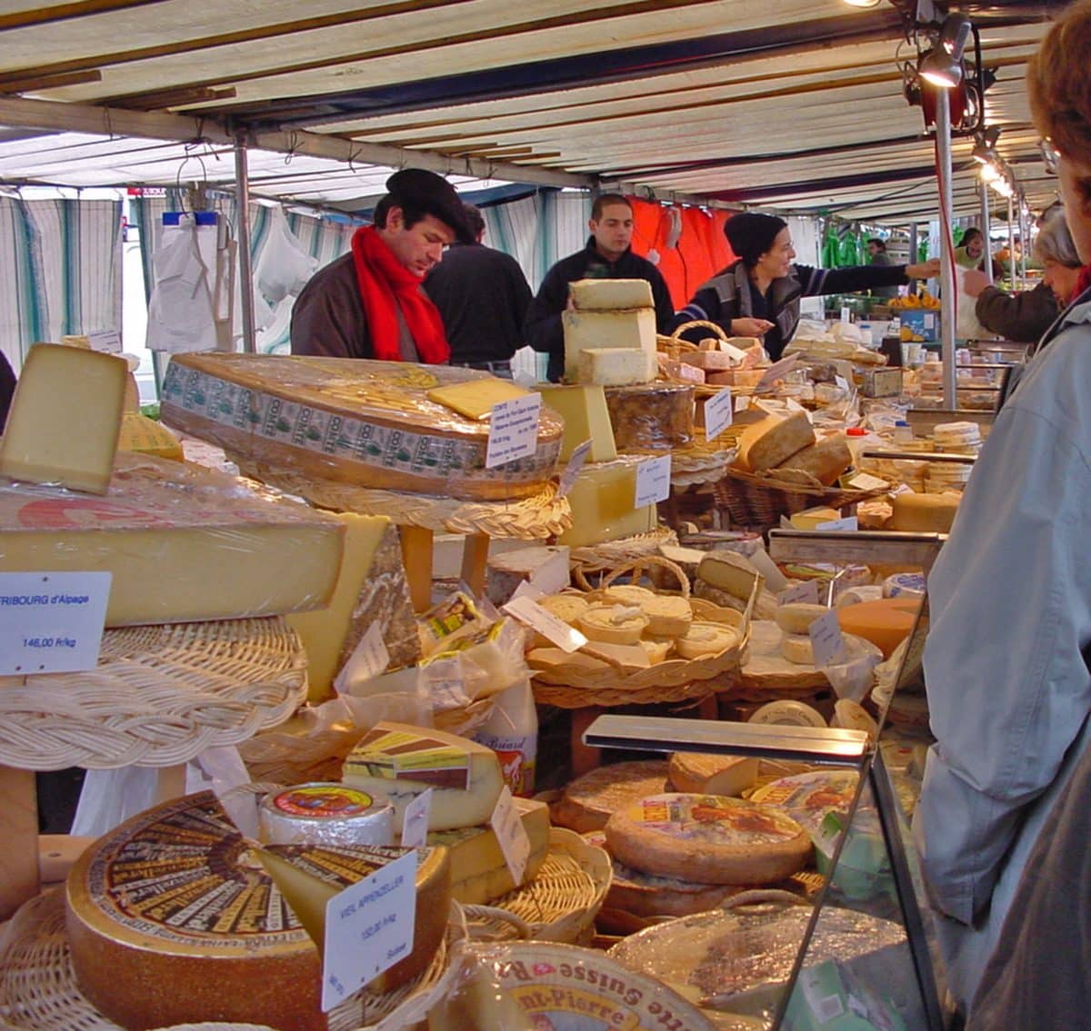 Shoppers selecting cheeses at an open-air market in Paris.
