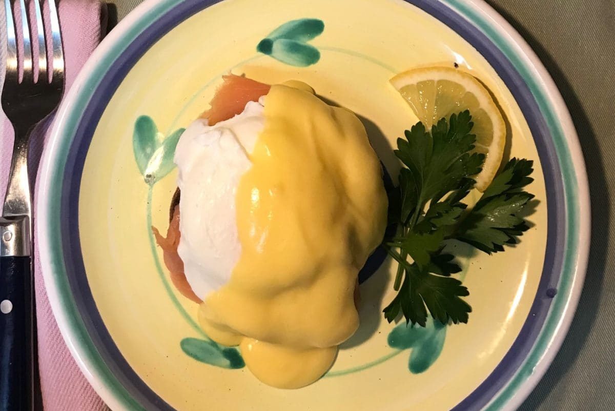Dish of Eggs Royale with hollandaise sauce and a side of parsley