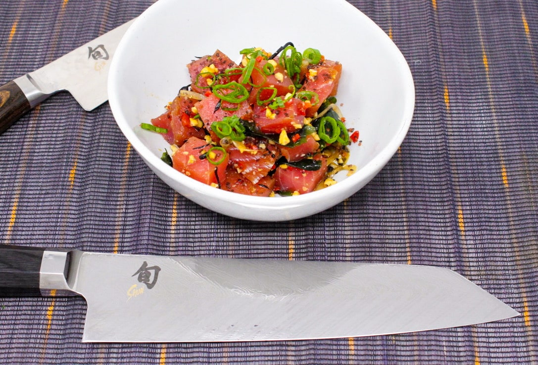 Fresh poke bowl beside Shun knives on a woven mat