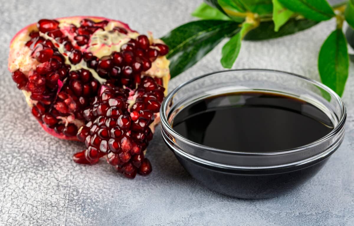 Pomegranate with bowl of molasses syrup
