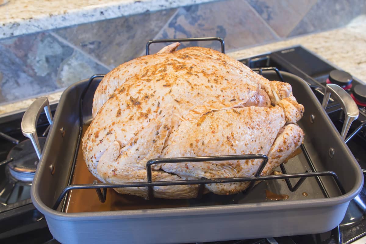 Uncooked turkey seasoned and placed in a roasting pan.