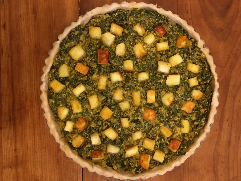 Spinach layered with fried paneer cubes in a quiche crust.