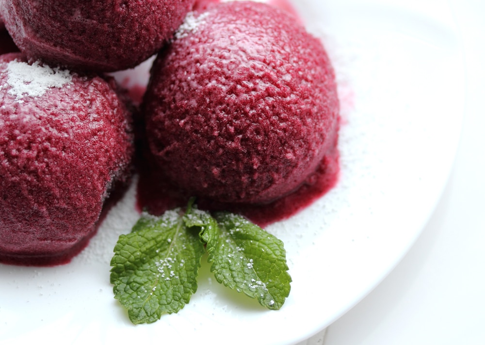 Close-up view of raspberry sorbet garnished with a mint leaf.