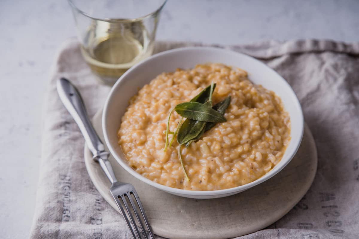 Bowl of creamy risotto garnished with sage.