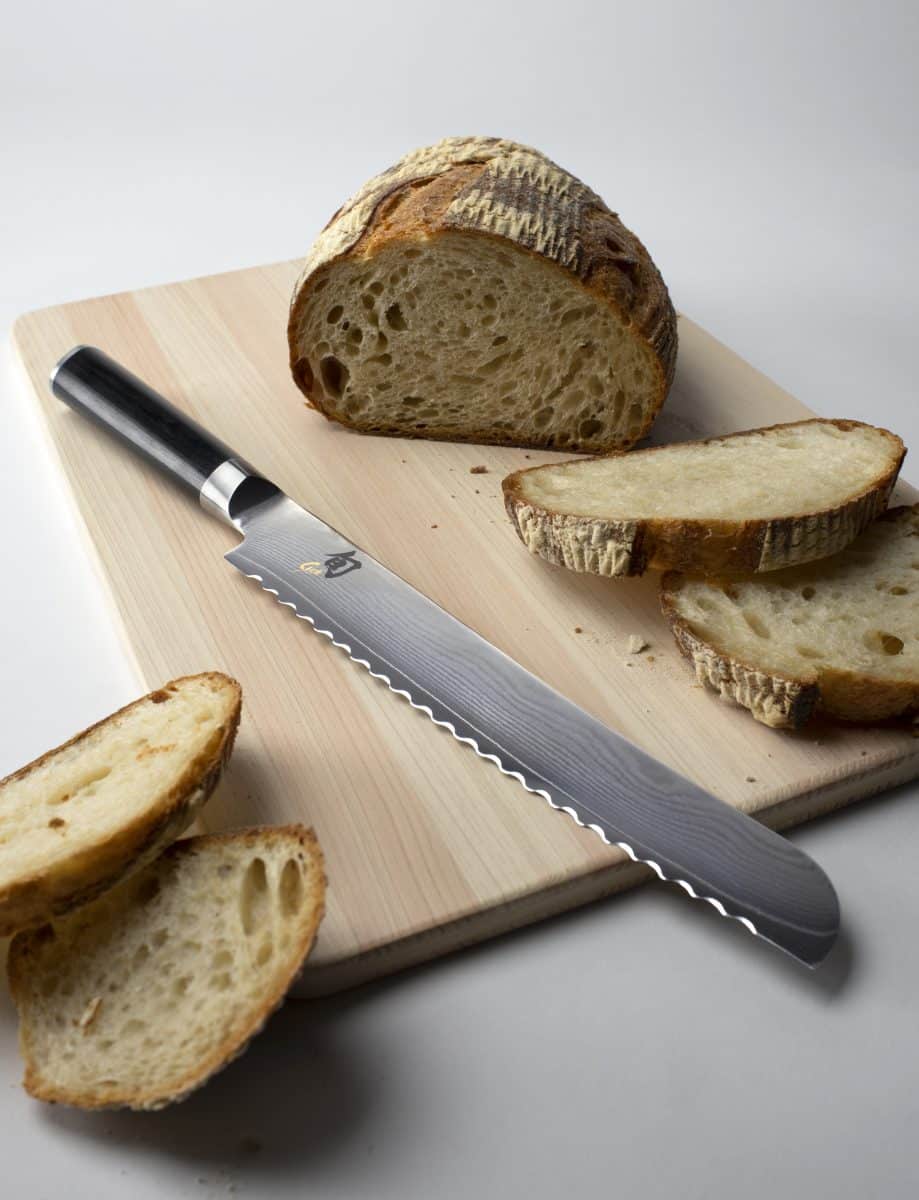 Freshly sliced sourdough bread with a serrated bread knife beside it.