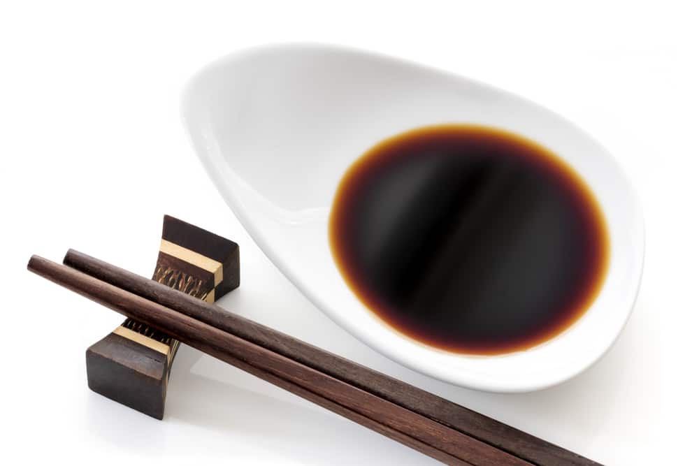 soy sauce in a white dish with chopsticks