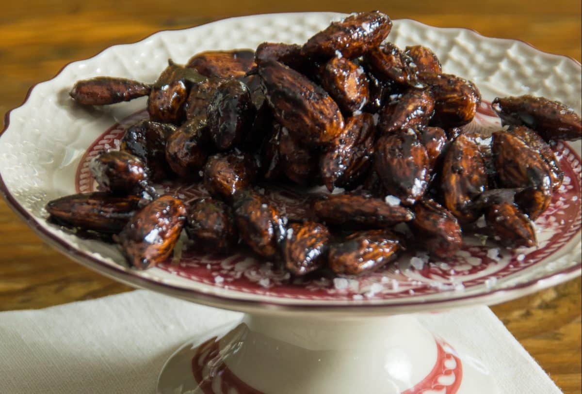 Dish filled with sweet and spicy almonds on a decorative plate