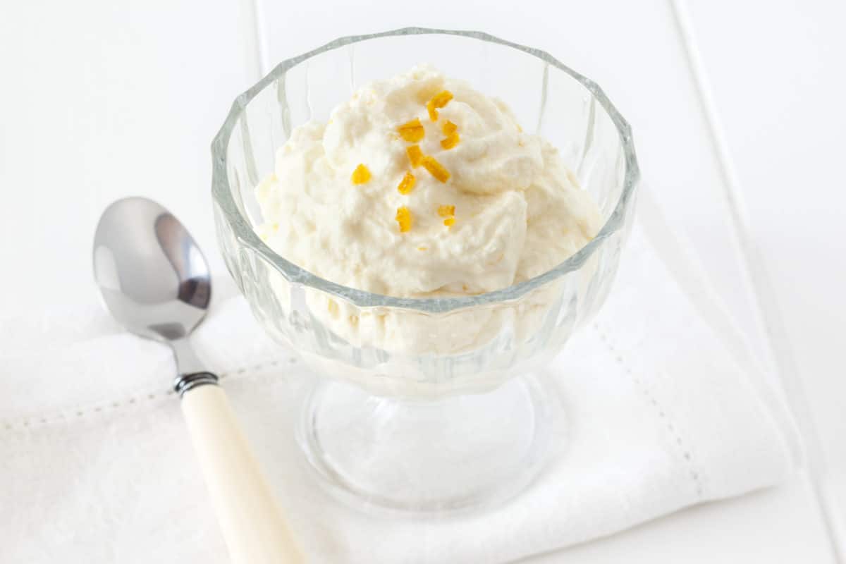 Whipped cream dessert garnished with orange zest in a bowl.