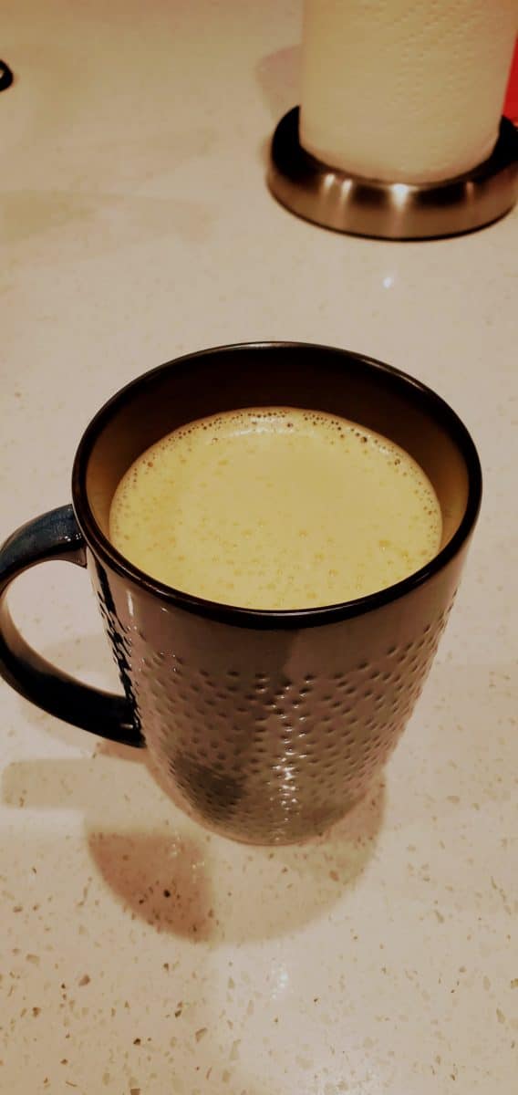 Close-up of a mug containing a frothy turmeric coffee.