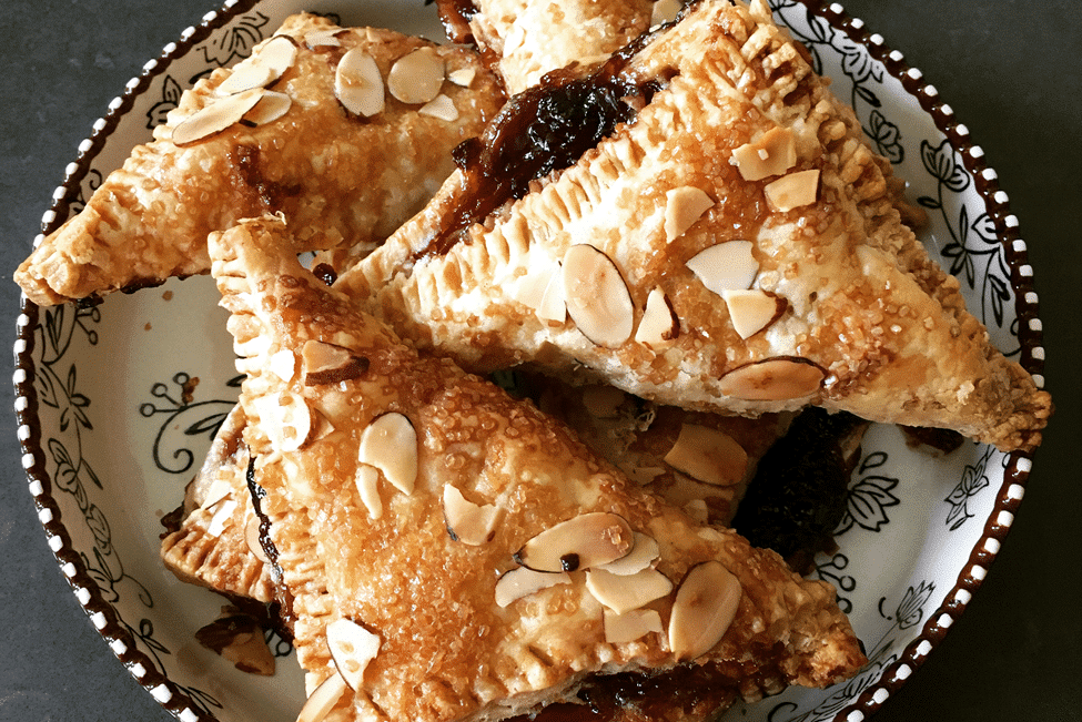 Fresh turnovers with almond toppings and jam oozing out.