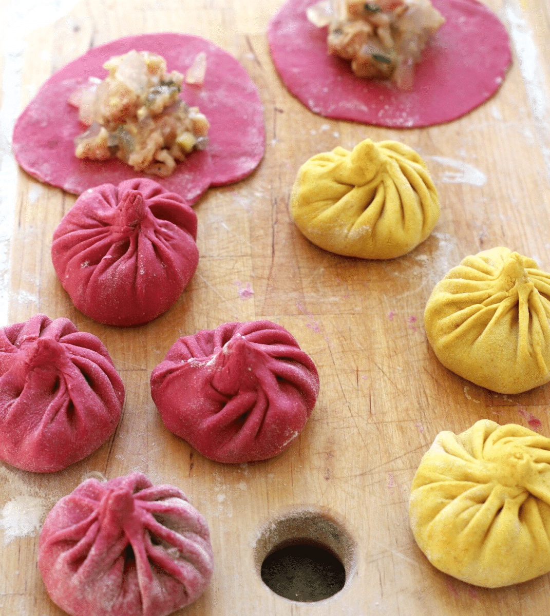 Colorful dumplings being prepared on a wooden board.