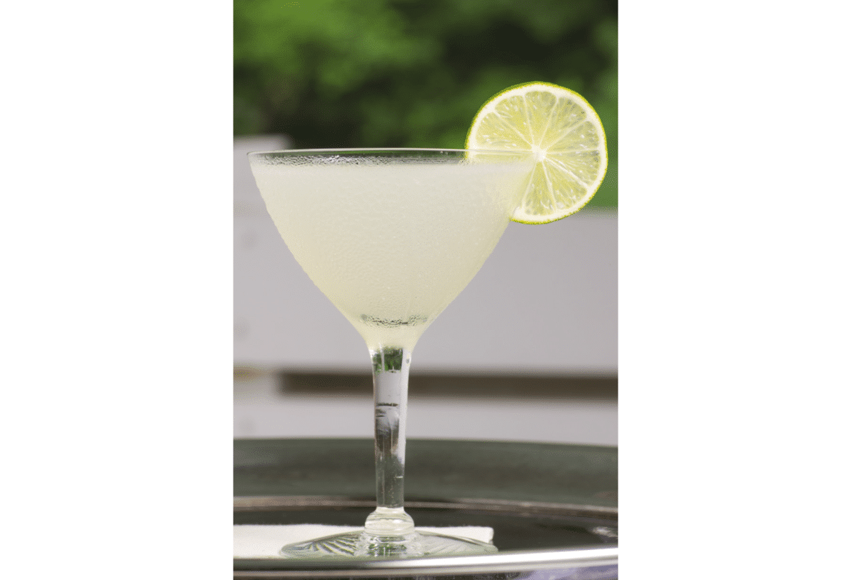 Close-up view of a daiquiri glass with a clear daiquiri and a slice of lime.
