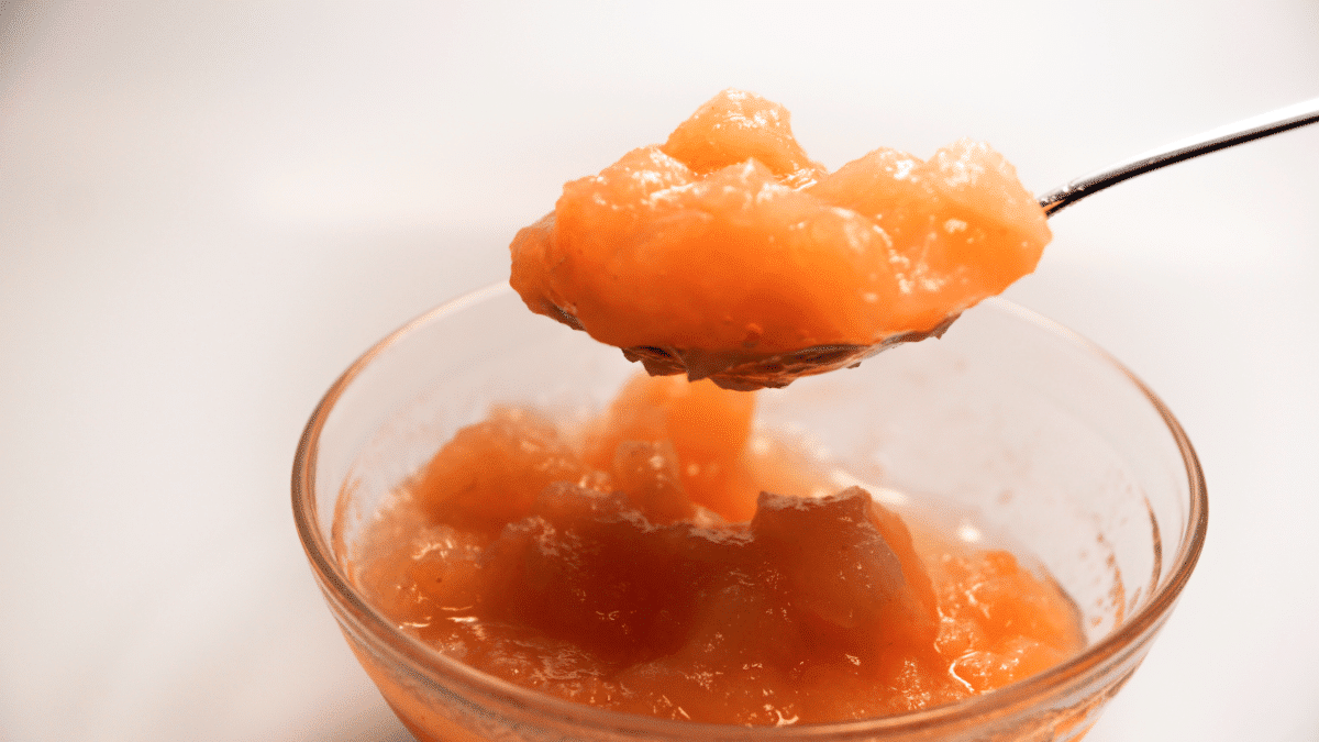 Close-up of a scoop of pineapple jam in a glass container.